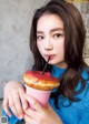 A young girl holding a donut with a straw in it.