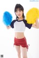 A woman in a cheerleading uniform holding two pom poms.