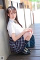 A young woman in a school uniform sitting on a porch.