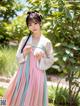 A woman in a pink and blue hanbok is posing for a picture.