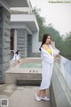 A woman in a white robe standing next to a pool.