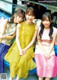 A group of three young women sitting on a blue couch.