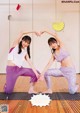 A couple of women doing yoga on a wooden floor.